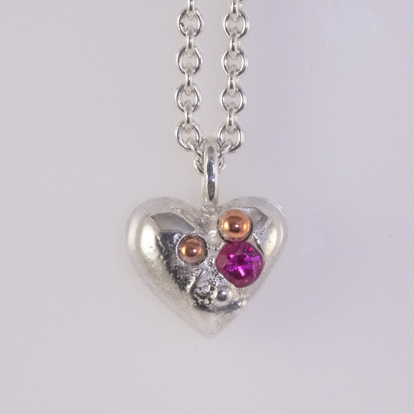 Sand-cast heart pendant with copper and zirconia details handmade by VerdeRame Jewels