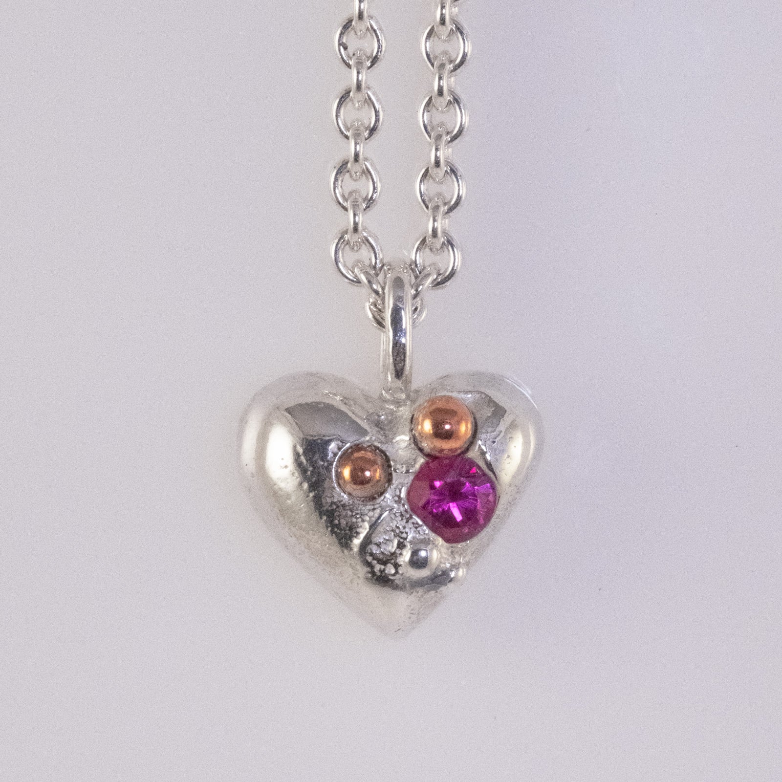 Sand-cast heart pendant with copper and zirconia details handmade by VerdeRame Jewels