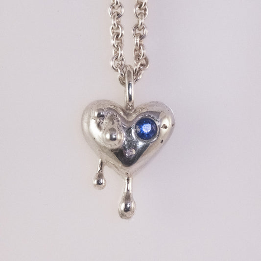 Front view of sand-cast silver heart pendant with small blue zirconia by VerdeRame Jewels