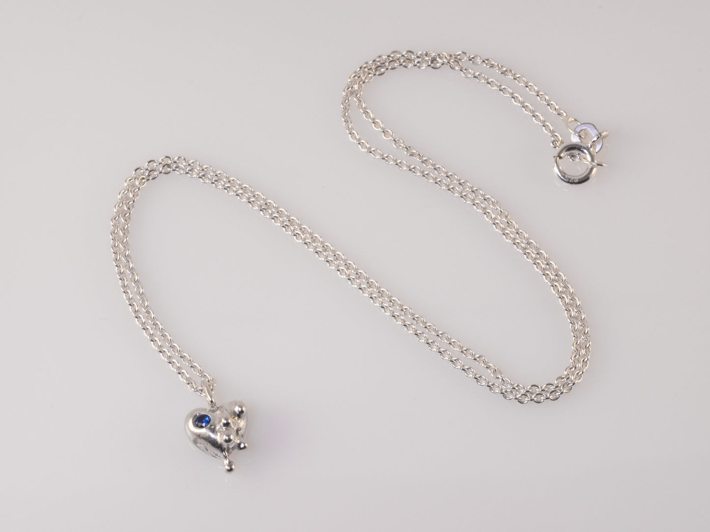 General view of sand-cast silver heart pendant with blue zirconia by VerdeRame Jewels