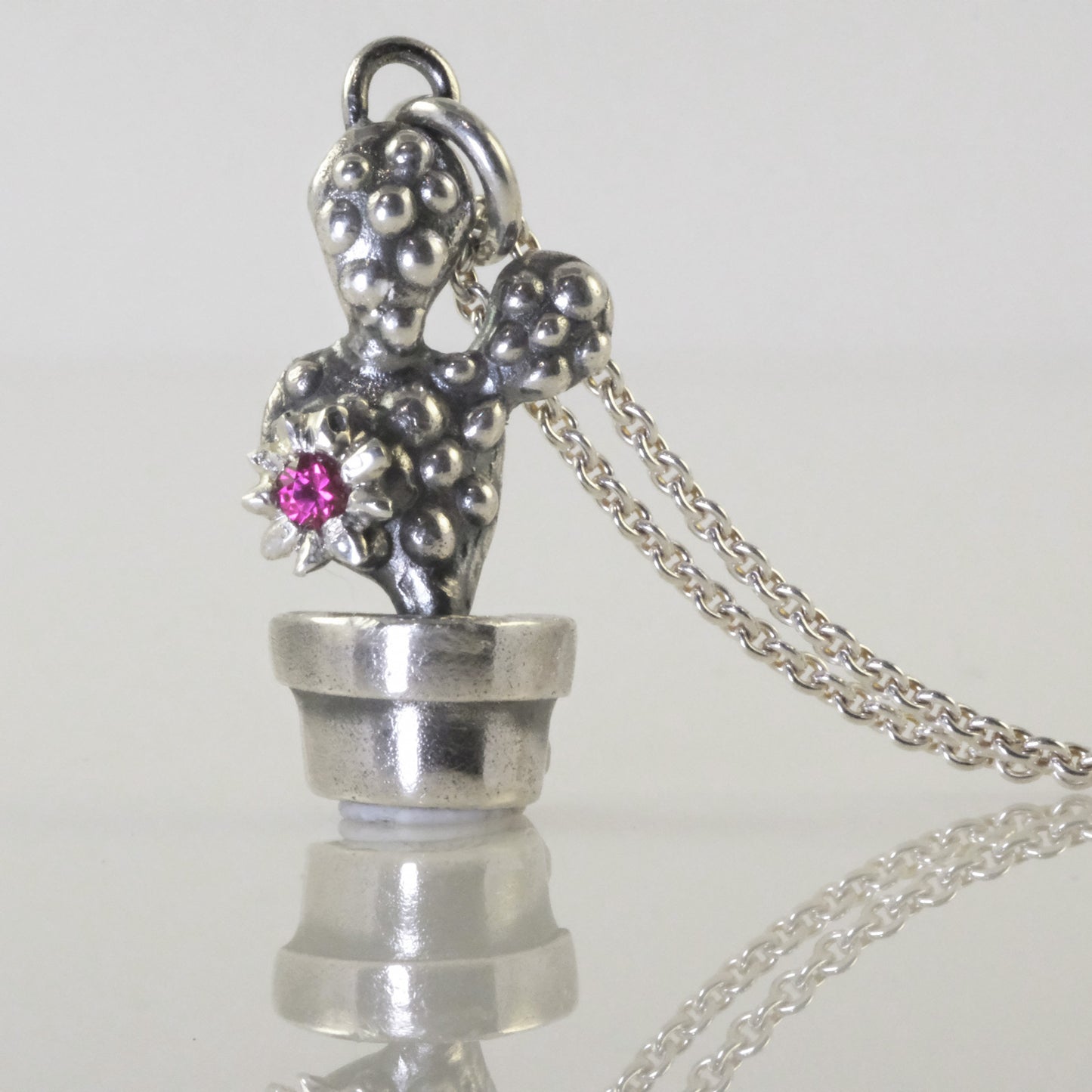 Detail of handmade silver cactus pendant with oxidised finish