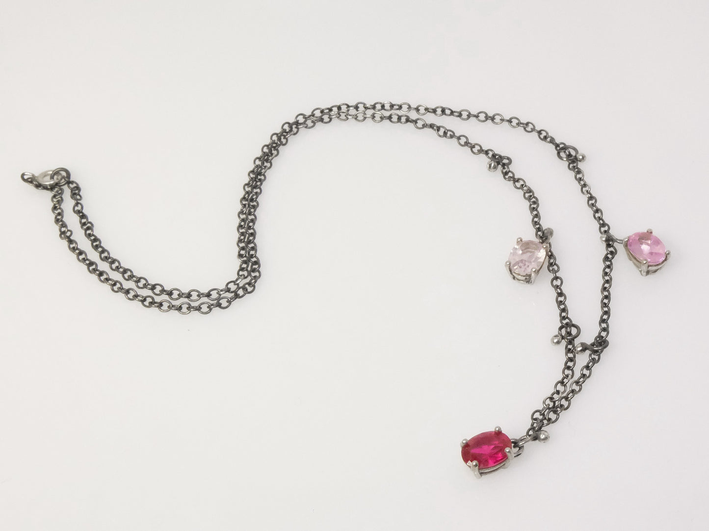 Elegant sterling silver necklace with oval-shaped crystals and small silver ball charms, draped on a collarbone.