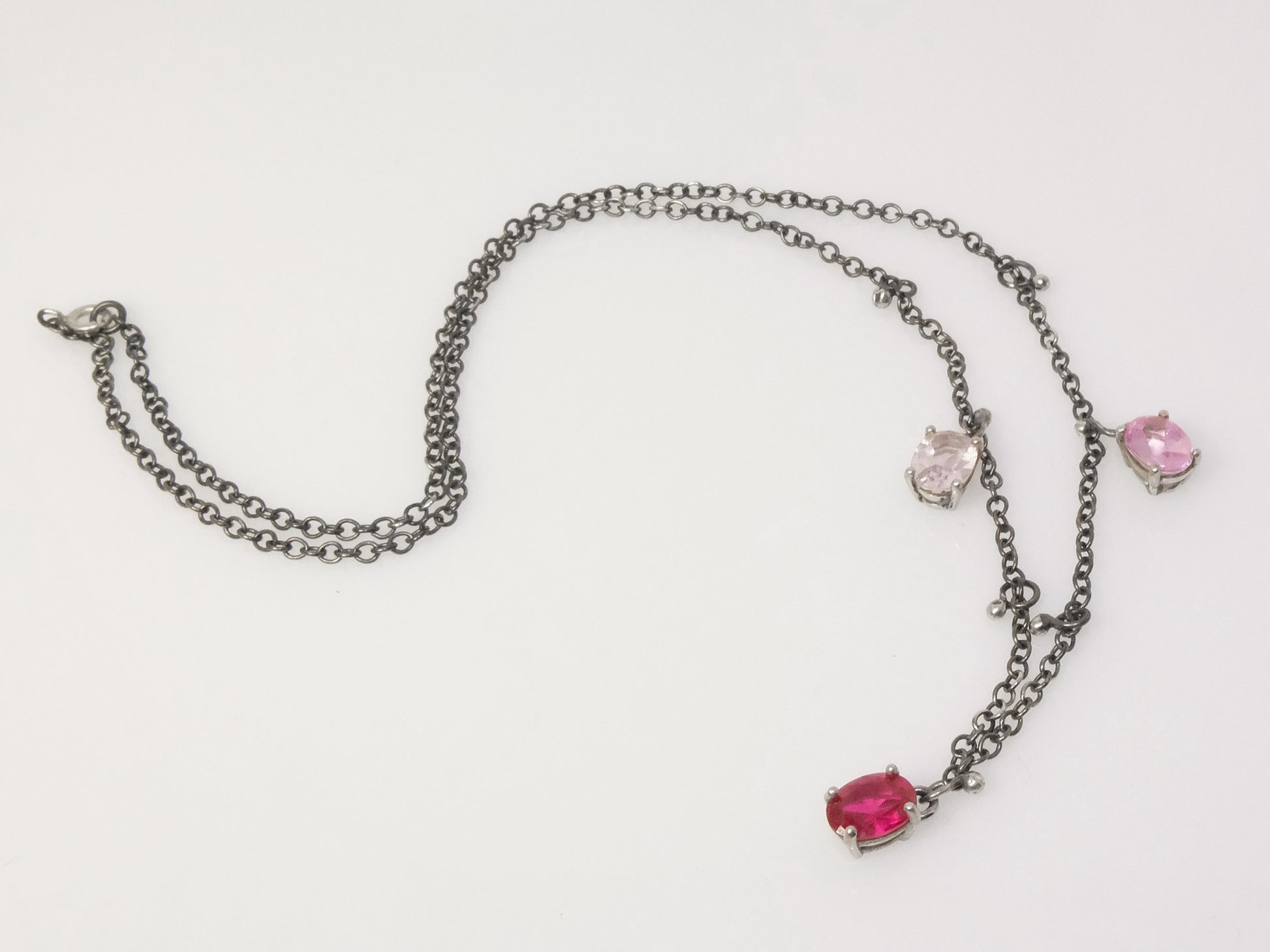 Elegant sterling silver necklace with oval-shaped crystals and small silver ball charms, draped on a collarbone.