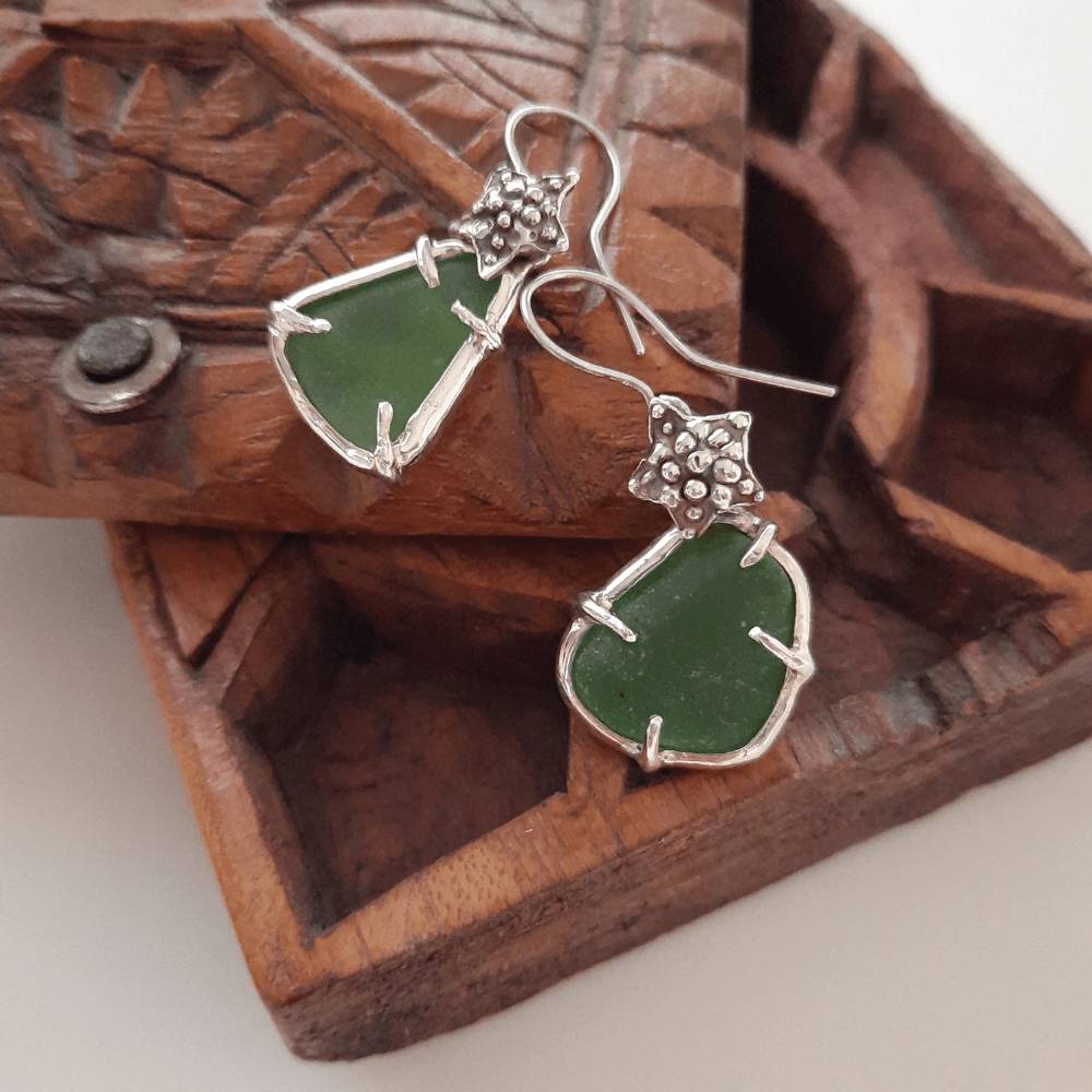 Detail of handmade silver starfish earrings with green sea glass