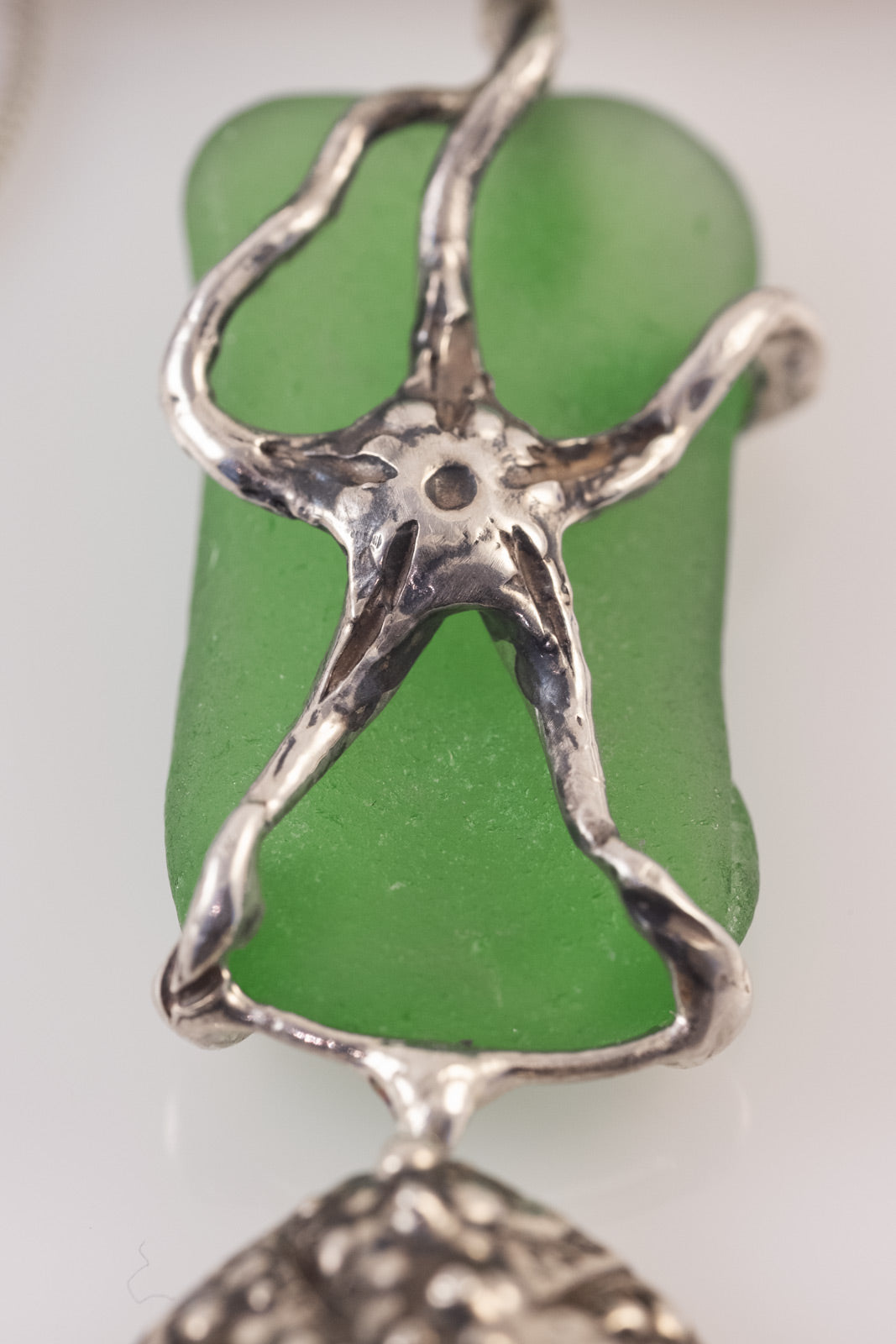 Detail of handmade silver starfish pendant with green sea glass