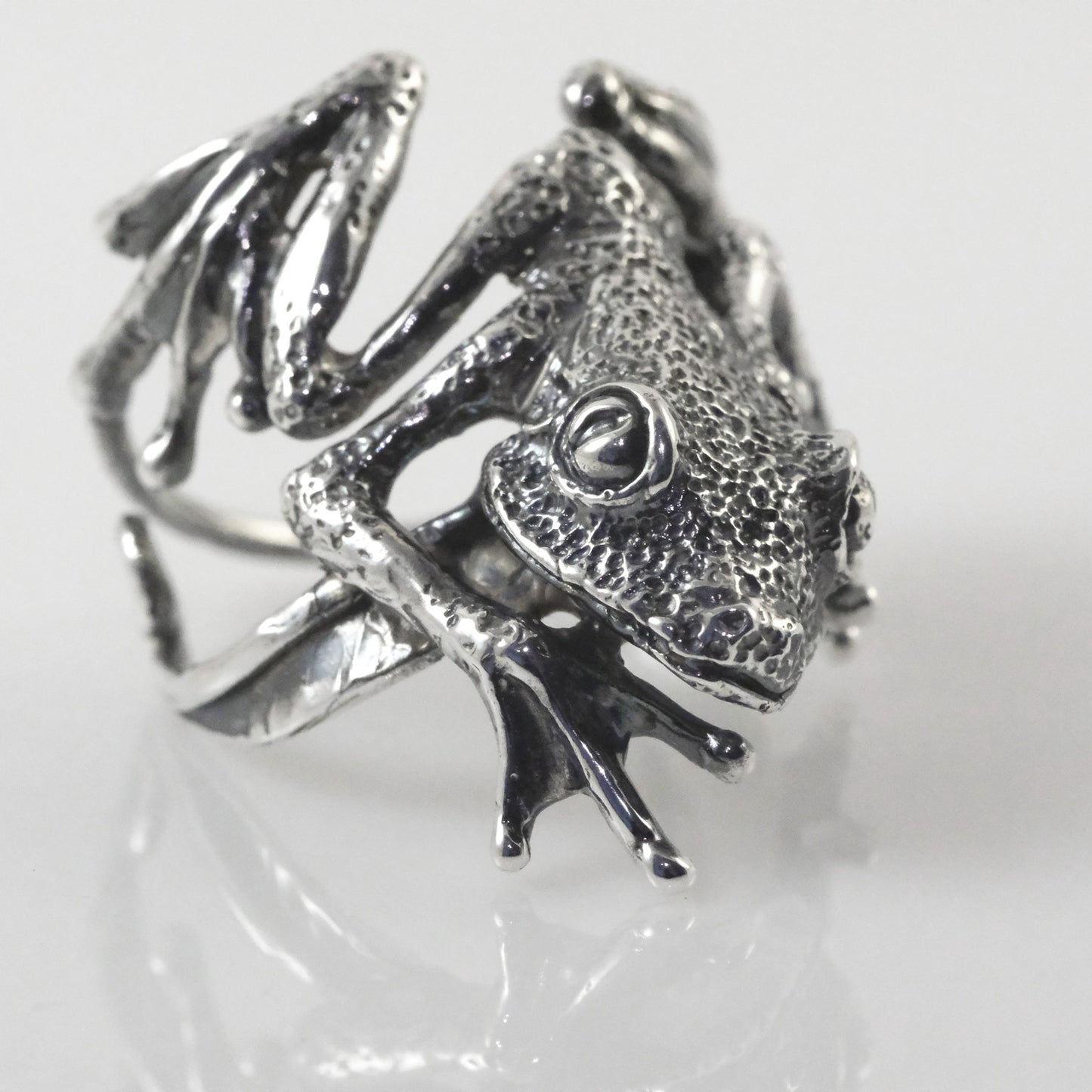 Close-up of artisan silver frog ring showing detailed miniature sculpture