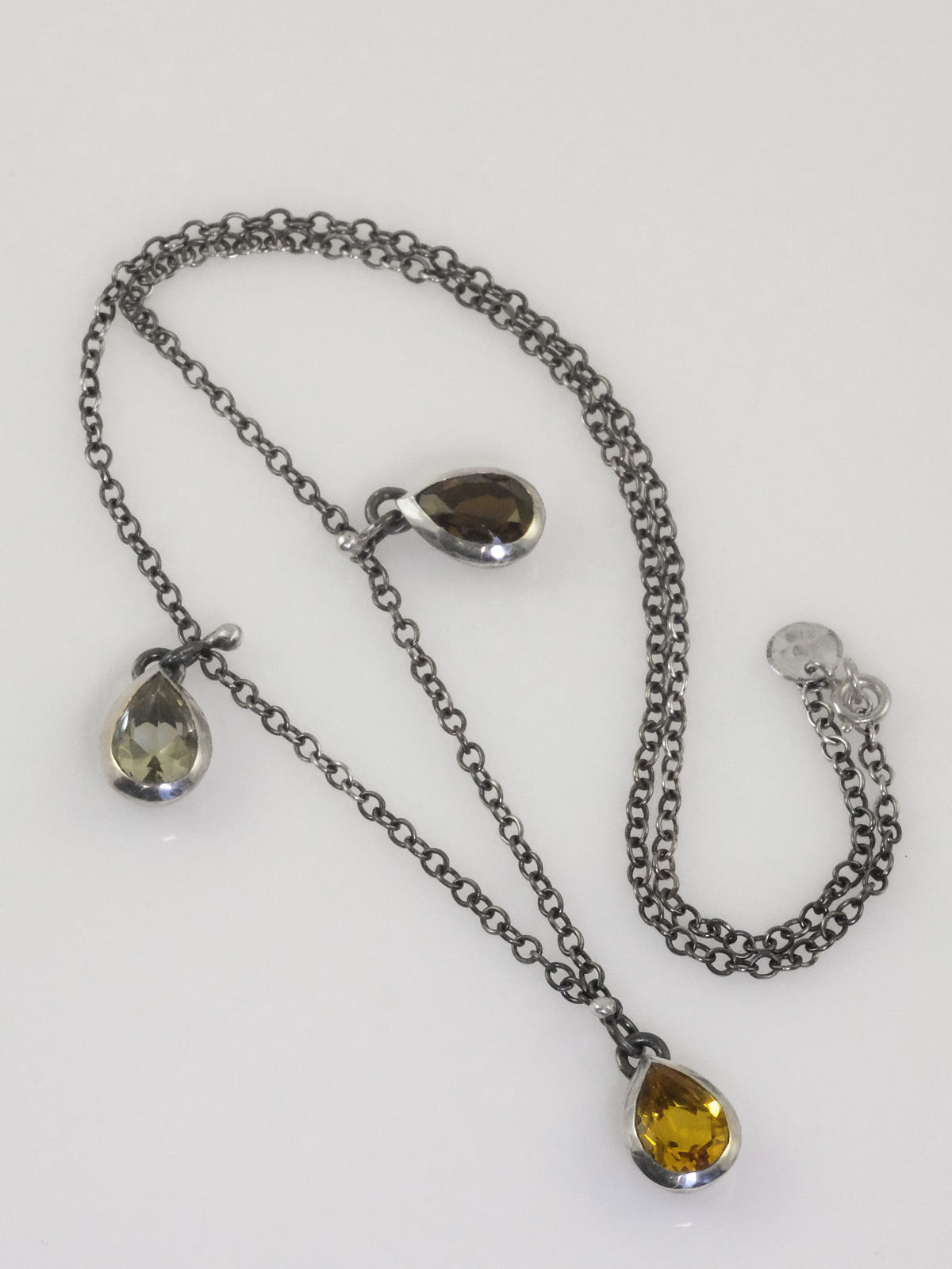 Handmade oxidised silver necklace with teardrop-shaped crystals in black, yellow, and pale green by VerdeRame Jewels.
