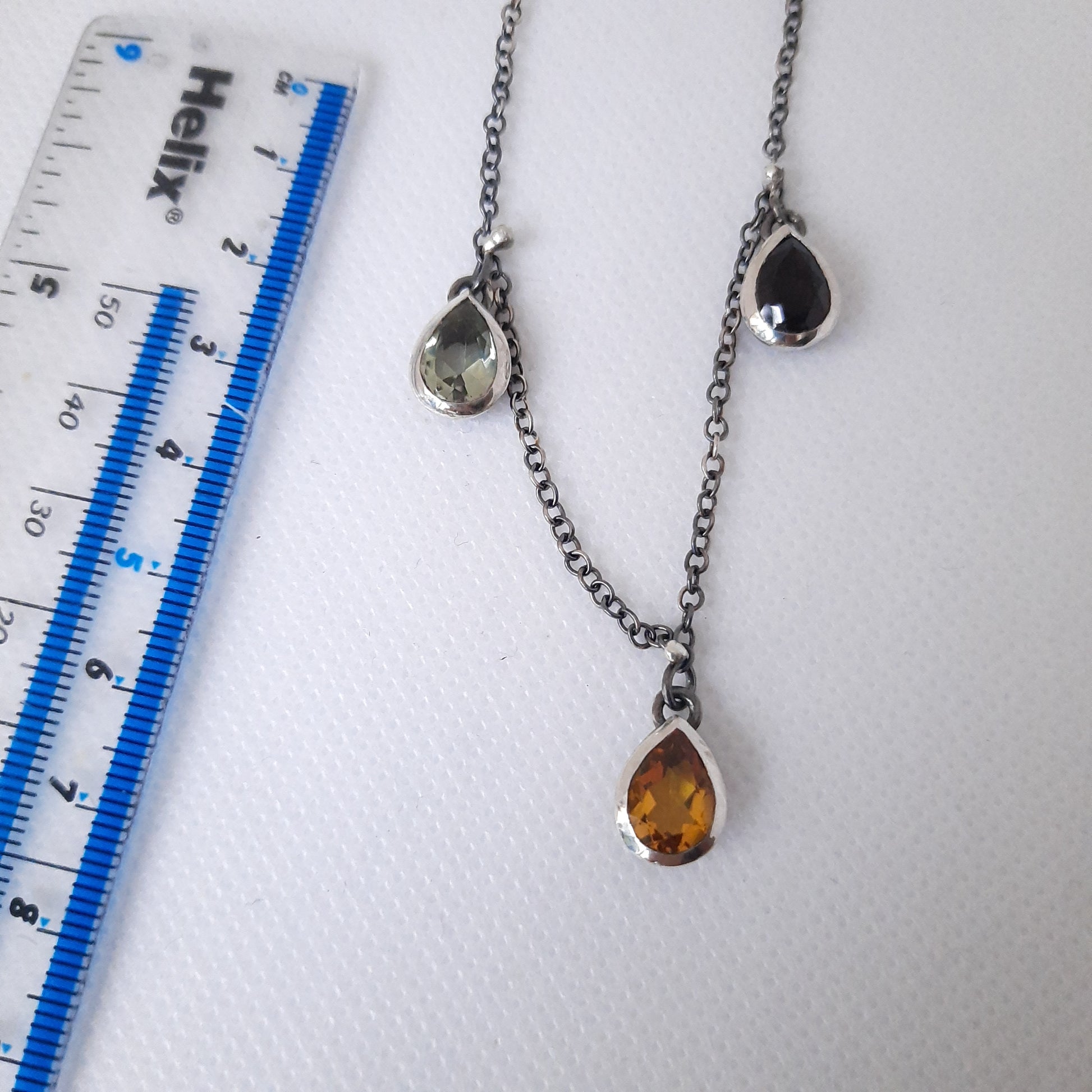 Detailed view of oxidised silver chain with teardrop-shaped crystal pendants showing craftsmanship and design.